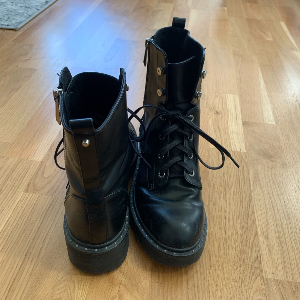 Black boots with lace design and zipper opening. Lug sole and studded design